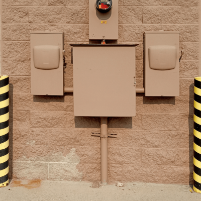 Servicios de Instalaciones eléctricas. Industrial electrical fuse box with warning stripes on an urban wall.